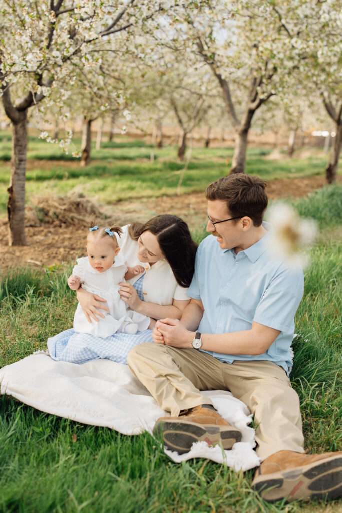 Family smiles amidst the blossoms at Rowley's Red Barn in Santaquin, Utah