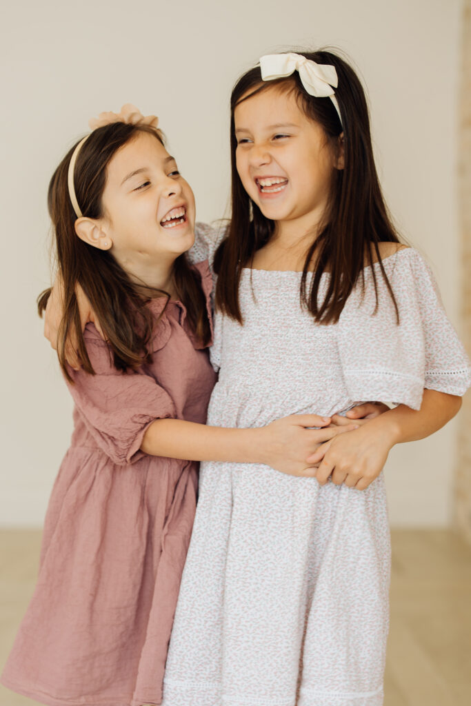 Sisters share a giggle at their family studio session in Sandy, Utah