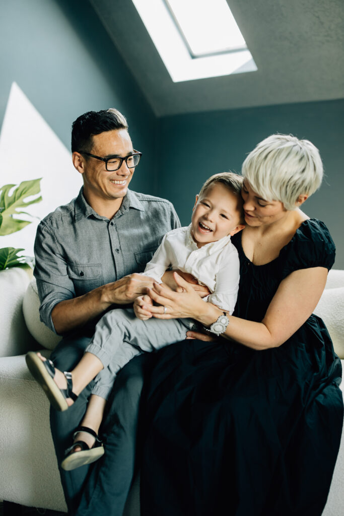family smiles in "The Gable" area of Brightwood Home Studios in American Fork, Utah