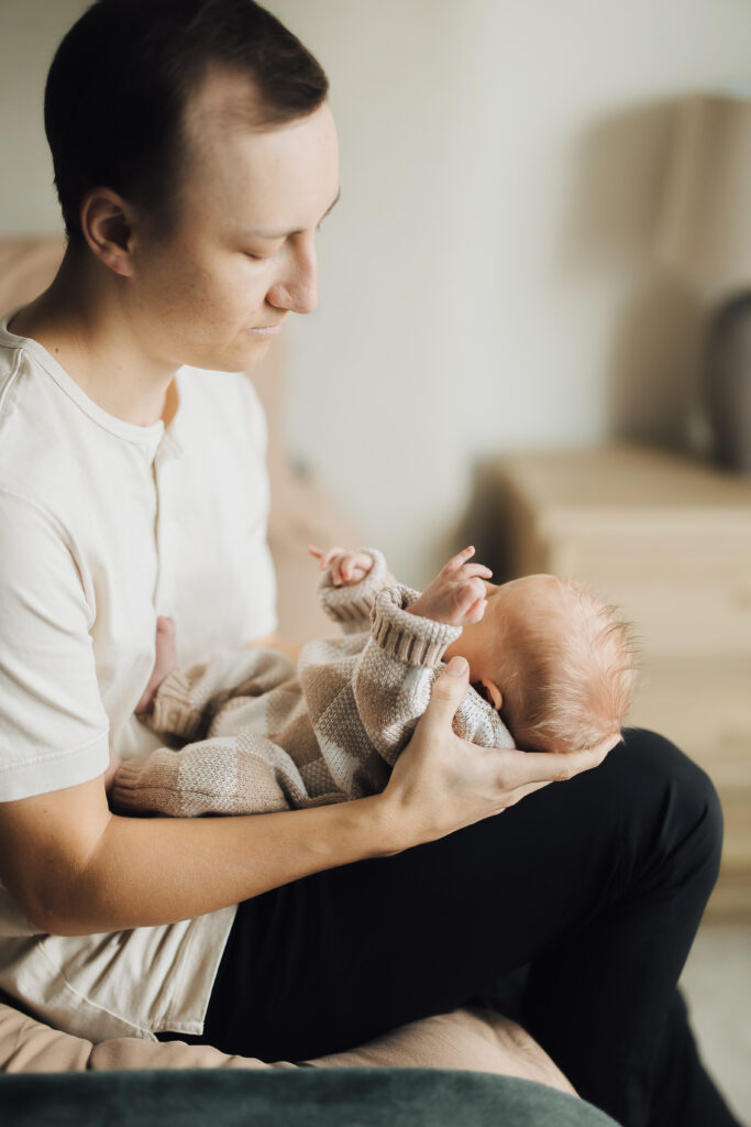 Dad snuggles newborn son in lifestyle newborn session in Saratoga Springs