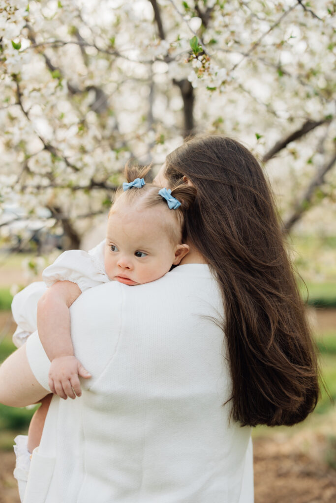 Mother and baby snuggle in a spring orchard mini session in Utah
