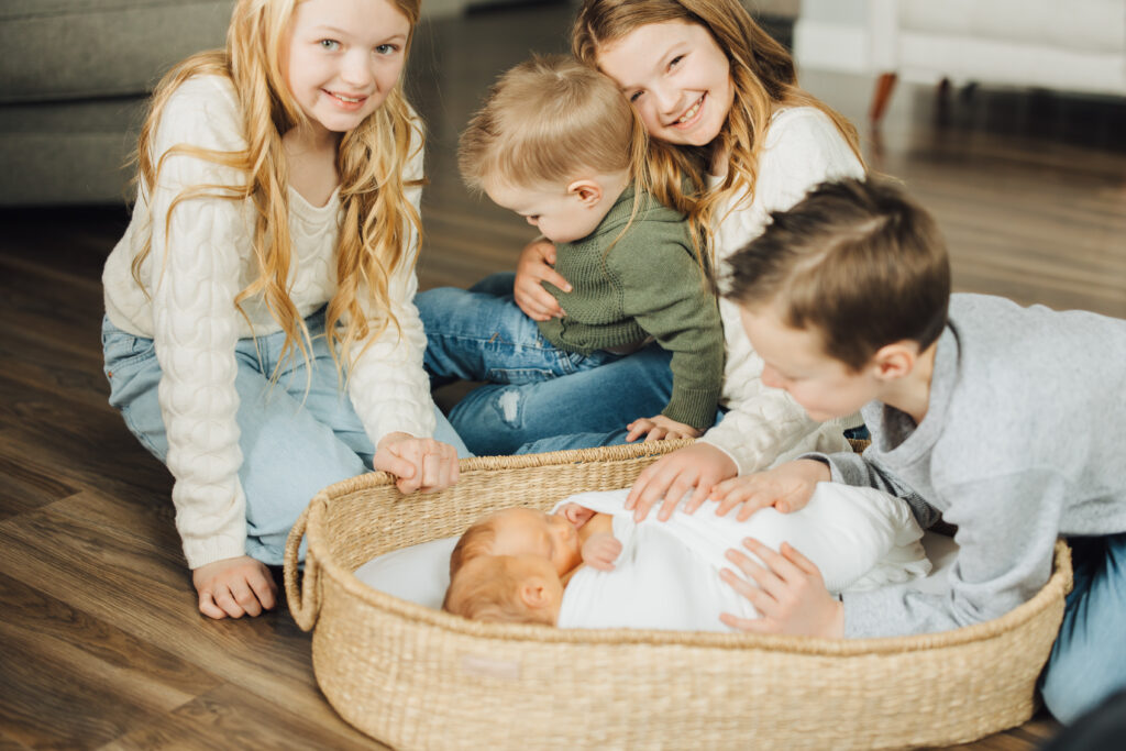 Siblings snuggle new baby brothers in twin lifestyle newborn session in Spanish Fork, UT.