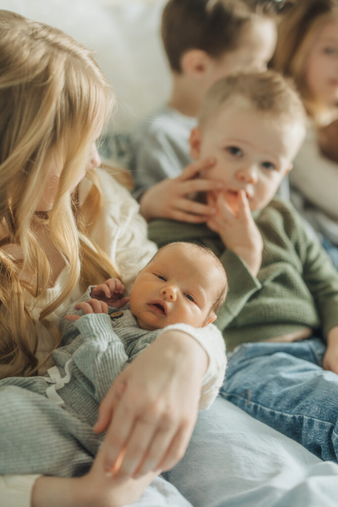 Siblings snuggle new baby brothers in twin lifestyle newborn session in Spanish Fork, UT.