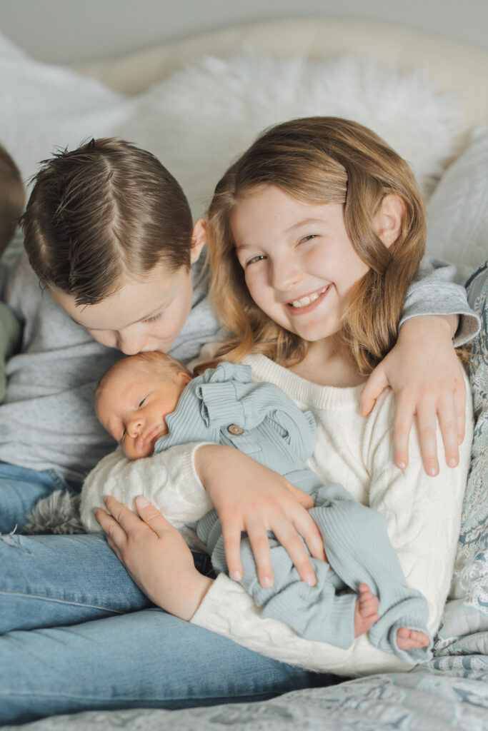 Siblings snuggle new baby brothers in twin lifestyle newborn session in Spanish Fork, UT.