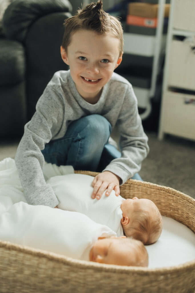 Brother snuggles new baby brothers in twin lifestyle newborn session in Spanish Fork, UT.